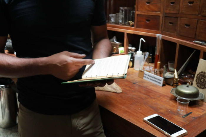 Johari opening his grandfather’s journal, which holds past trade secrets about mixing proportions and suppliers. Johari shares that his grandfather used to get ingredients from all over the world.