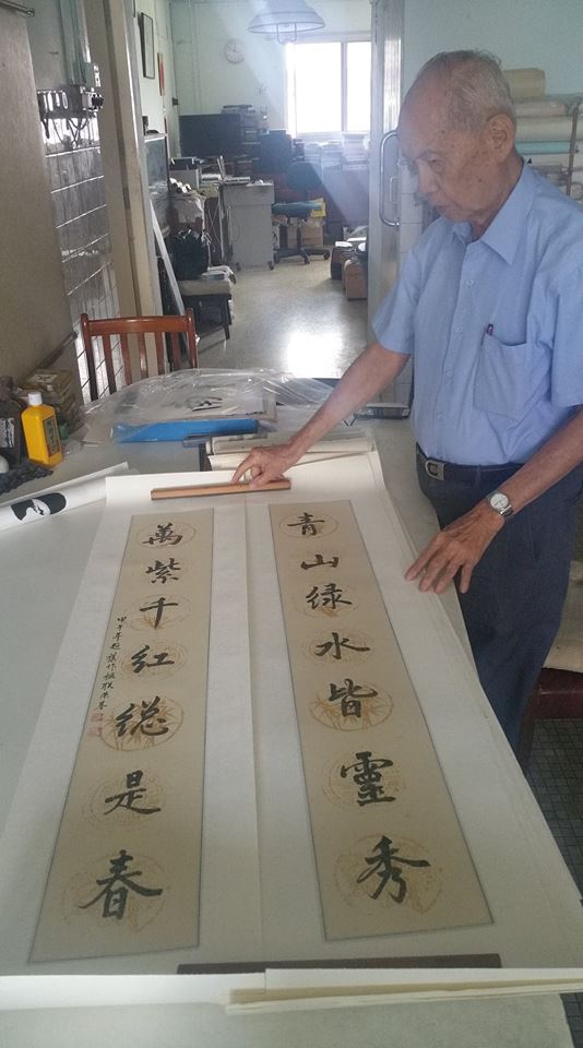 Dr Leong Weng Kee with a couplet that he has written calligraphy on. The practice combines visual and literary art, with each Chinese character not only being a word but also a pictorial representation of its meaning.