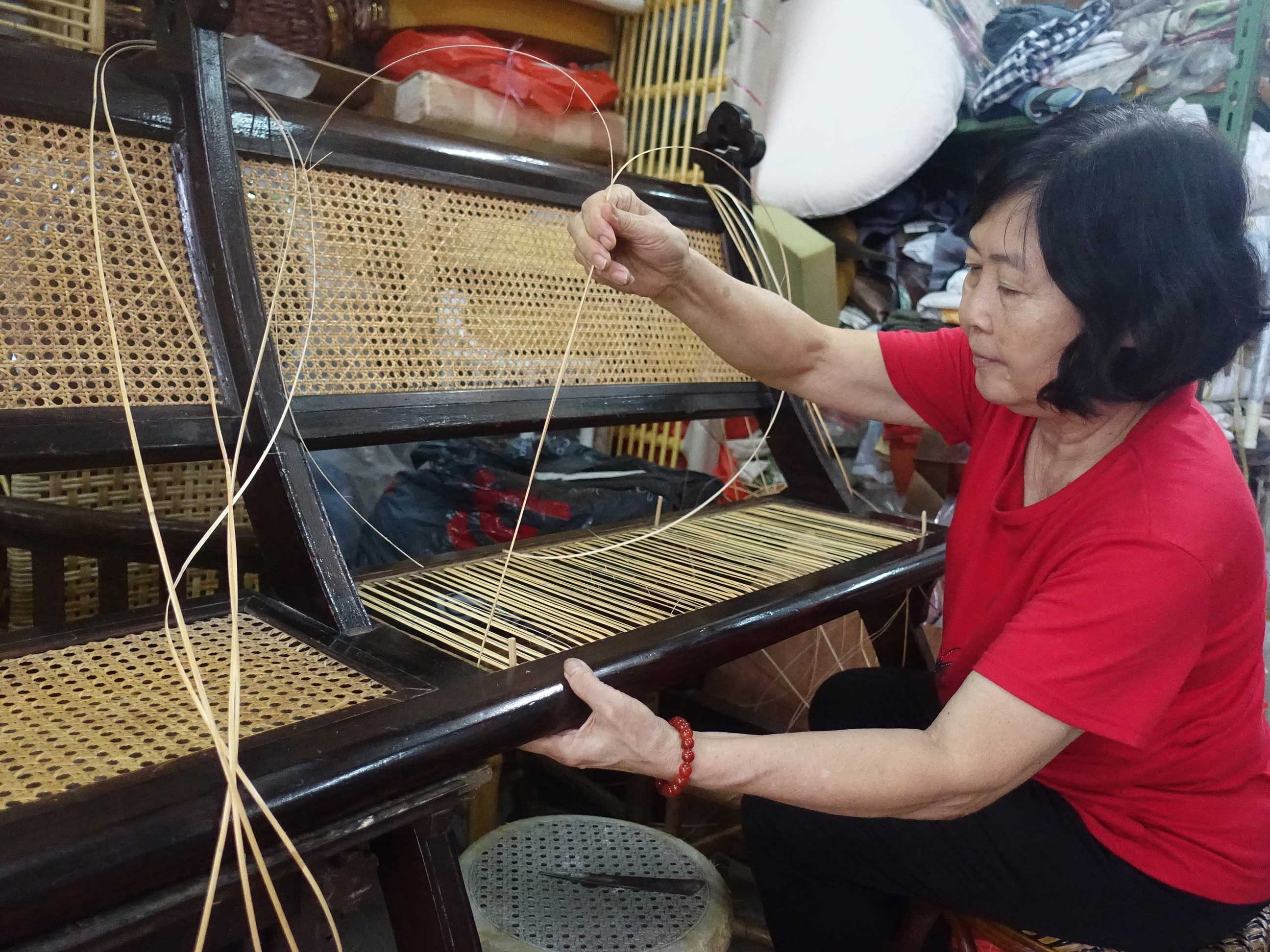 Mdm Lee Joon repairing a rattan seat of a wooden pew for the Armenian Church.